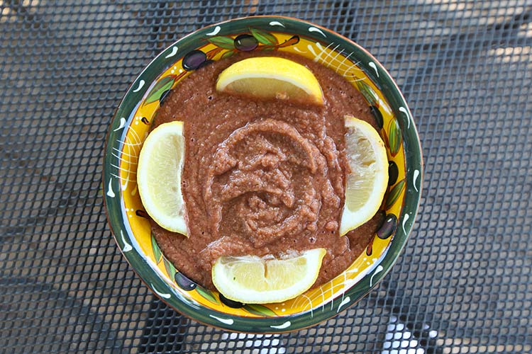 Gazpacho served with lemon wedges.